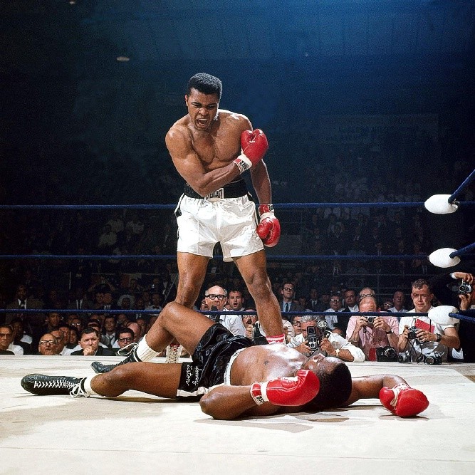 93. Ali và Liston: Muhammad Ali gây sốc cả thế giới Quyền anh khi đánh bại Sonny Liston vào tháng 2/1964 và đoạt chức vô địch hạng nặng WBC, tuy nhiên WBC cho rằng Liston bị chấn thương vai khá nặng khi thi đấu và yêu cầu một trận tái chiến. Họ lại gặp nhau vào ngày 25/2/1965, 6 tháng sau khi Ali bị chứng thoát vị và phải nhập viện. Trận đấu không chỉ được nhớ đến là trận đấu tranh đai có lượng khán giả thấp nhất trong lịch sử, nó chính là trận đấu tranh đai NGẮN NHẤT trong lịch sử. Cuối hiệp 1, Liston bất ngờ ngã xuống bởi một cú đấm (sau này được gọi là “Cú đấm ma”) mà không ai ở gần sàn đấu nhìn thấy. Trọng tài bị bối rối khi Ali từ chối quay về góc võ đài của mình và đứng sừng sững trước đối thủ đã ngã, chỉ tay và hét lên với Liston: “Đứng dậy và đánh đi, thằng khờ!”. Khoảnh khắc được nhiếp ảnh gia Neil Leifer chụp được và xuất hiện trên bìa của ấn phẩm đặc biệt “Những bức ảnh Thể thao vĩ đại nhất của Thế kỷ”.
